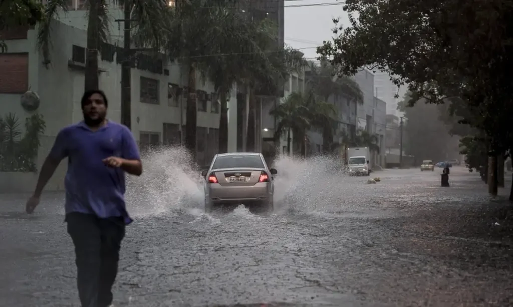 Alagamento em via da cidade de São Paulo durante chuva forte, com alerta do CGE