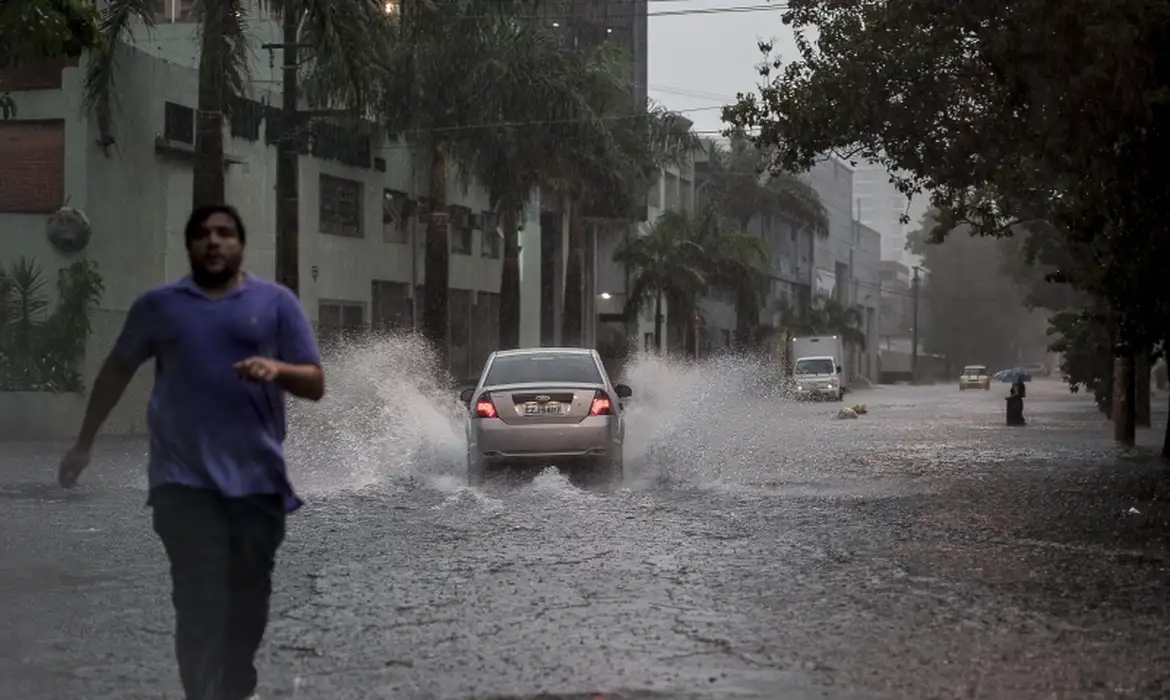 Alagamento em via da cidade de São Paulo durante chuva forte, com alerta do CGE