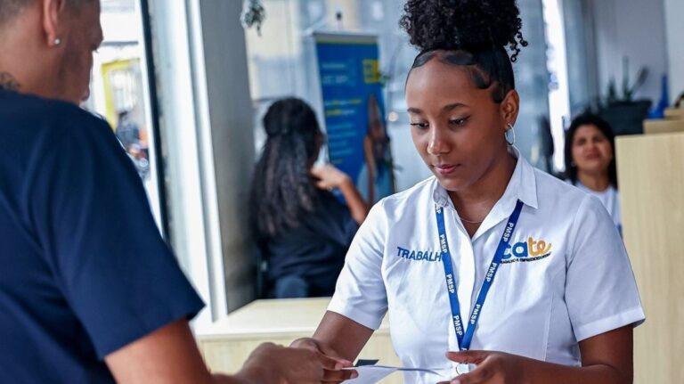Fachada de uma unidade do Cate em São Paulo com fila organizada de candidatos portando carteiras de trabalho