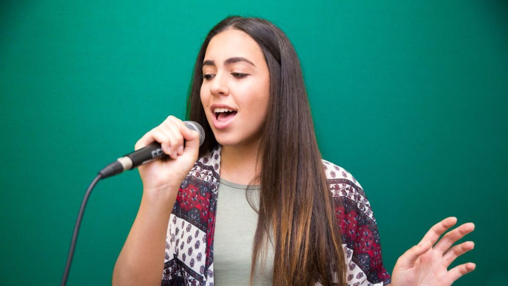 Pessoa cantando e mostrando uma sobrecarga vocal