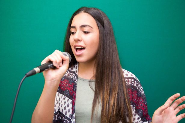 Pessoa cantando e mostrando uma sobrecarga vocal