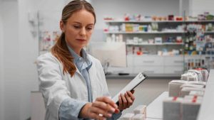 Profissional da área farmacêutica organizando medicamentos em farmácia