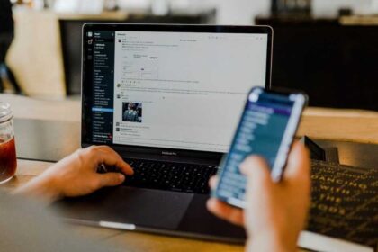 Pessoa utilizando smartphone e computador simultaneamente, ilustrando os efeitos do excesso de estímulos digitais sobre a atenção e a saúde do cérebro