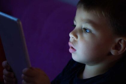 Criança utilizando dispositivo eletrônico, hábito que pode provocar olhos cansados e outros desconfortos quando há excesso de tempo diante das telas