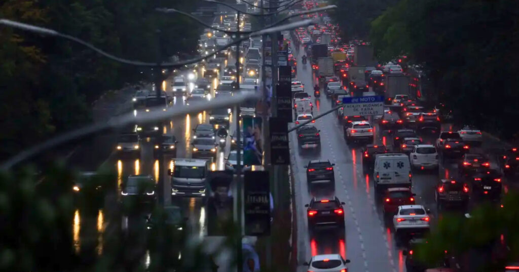 Trânsito de veículos em São Paulo durante chuva intensa, condição que pode reduzir a velocidade média em até 14,8%